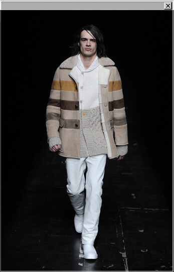 Sheepskin coat with contrasted horizontal stripes worn with a two-tone knitted cardigan in wool, jeans in cotton, a leather key holder and hand-painted leather boots.