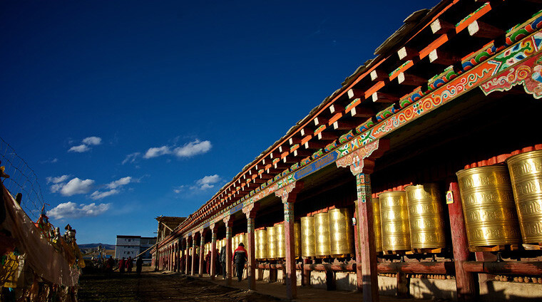 亚青寺建在四面环山的草原湿地上，有数千间信徒居住的小木屋，纵横交错的河流包围了整个寺庙的建筑群，每当清晨或黄昏，炊烟弥漫，河水闪耀着金光，颂经声随风远远传来，犹如天籁，动人心弦。