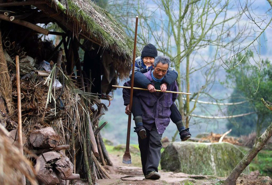 2月20日，雷婆婆年纪大了走不动山路，老谢就背着她走。重庆合川区古楼镇净果村白岩沟水库岸边，青龙山半山腰上住着一对老妻少夫，男的52岁，女的80岁。24年前，当他们决定走到一起时，亲友们都觉得年轻男人是“搞起耍”，劝他们散了。拗不过这对老妻少夫，大家让男人签下“合同”，要他保证不虐待老婆、不抛弃老婆，还要为老婆养老送终。