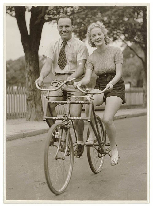 少了一个人车就会倒掉，很有寓意的情侣单车~ Man and woman on a Malvern Star abreast tandem bicycle, c. 1930s.