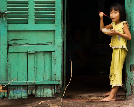 Young girl eats in a doorway in Vietnam