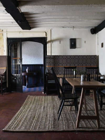 Ilse Crawford (of Studioilse) designed the dining room at the Olde Bell Inn, which features black-painted ceiling beams, chairs, and doorways.