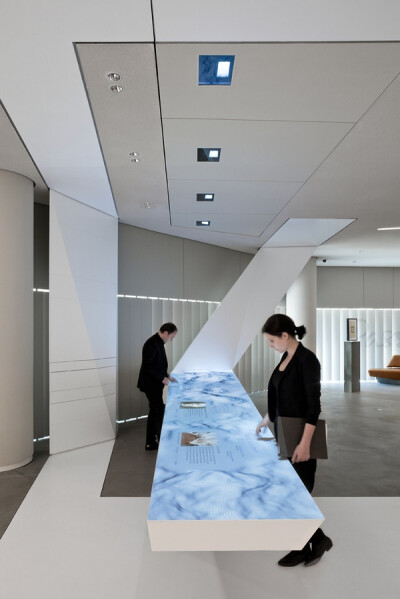 ART+COM 还设计了第四组装置，在主要入口楼梯的尽头，以同样的方式，一面形象墙由一系列多边形镜面组成，起初参观者只能看到一面凌乱的蓝色镜面墙，当逐渐步上楼梯到达特定视点，镜面墙呈现出德意志银行 logo 图形。