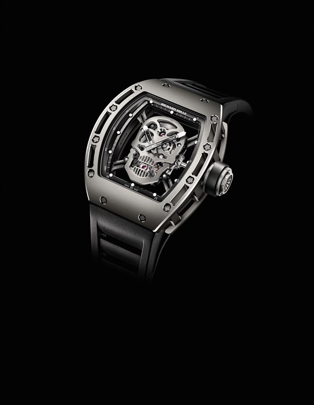 Richard Mille RM 052 颅骨陀飞轮限量版腕表 RM 052颅骨陀飞轮腕表采用规格为42.70毫米×50.00 毫米×15.95毫米规格表壳，表壳需要历经 255 道机械加工工序，由20 颗 5 级钛合金花键螺丝及抗磨损316L 不锈钢垫圈组装而成。表圈和表壳底盖上打有孔洞，通过以此减轻表壳的重量，这在 Richard Mille 尚属首例。搭配扭矩限定表冠，这种表冠有助于强化安全系数，防止意外过度上发条，从而避免造成各种潜在损坏，诸如上发条旋柄折断或是发条盒的发条压力过大。镂空表盘，表盘配备时、分显示，中央赫然置有一面骷髅，骷髅被完美的融合于机芯之中。颅骨的上、下颚骨托持陀