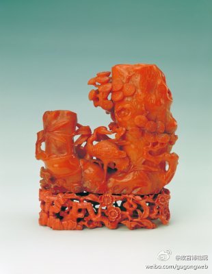 蜜蜡鹤鹿同春双孔花插，清，通高18.7cm，长16.5cm，宽6.3cm。花插为蜜蜡制成，雕作松竹椿形，为双孔，大孔是松树椿，松枝茂密，小孔为竹椿，并有鹤、鹿及灵芝。底配以镂雕染牙红色桃花枝座。此件花插颜色纯正，雕琢…