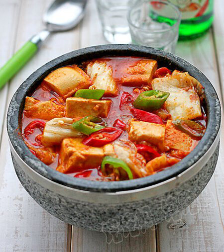 【韩式辣白菜豆腐汤】 材料 南豆腐 250克 青红尖椒 1个 韩式辣椒酱 20克 辣白菜 100克
<br />色拉油 20克
<br />鸡精
<br />作法
<br />1.豆腐过水冲洗一下，分切成正方小块；
<br />2.辣白菜切成小片，青红尖椒斜切成圈；
<br />3.石锅置于火上，锅底倒少量油，中火加热； 4.油温八成热时，下入青红椒圈扒炒一下； 5.然后下入辣白菜，翻拌扒炒均匀； 6.加入韩式辣椒酱，加入半锅水，搅拌均匀； 7.待到汤汁煮至沸腾时，下入豆腐块； 8.拌匀后煮至再次沸腾