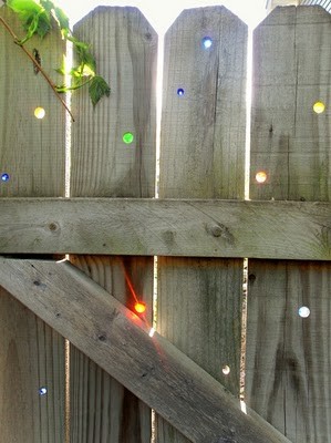 drill holes into fence boards and press colored marbles into them for lovely sun art!