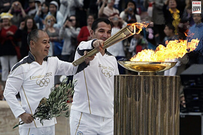 李宁参与圣火传递 2012年5月17日，火炬手皮洛士-迪马斯(右)和李宁(左)在雅典“泛雅典”露天体育场上进行圣火传递的交接仪式。