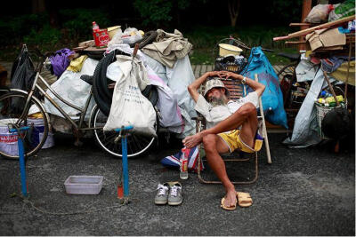 中国，上海：一位修理自行车的男子在等客人的时候在椅子上睡着了。