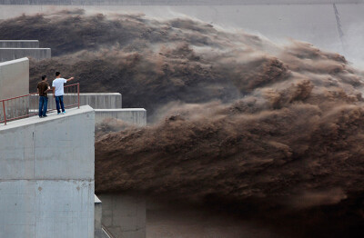 24 hours: Luoyang, China: Local residents watch as sediment-laden floodwaters gush