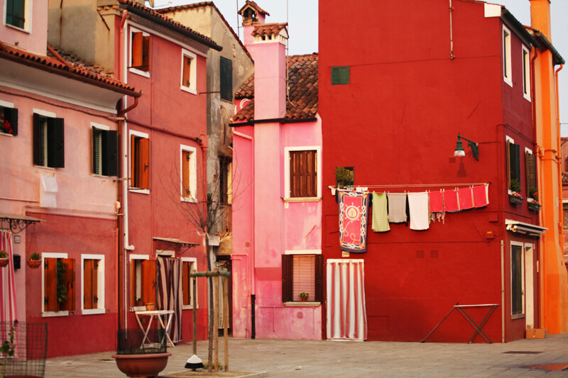 【Burano 布拉諾島】是義大利威尼斯潟湖上的島嶼，以手工蕾絲和彩色房子聞名於世。據說1481年達芬奇從希臘小城鎮Lefkara購回米蘭大教堂使用的壇布後，引進了花邊蕾絲，此技術於該島上生產製作，日後逐漸成為當地特產。彩色的房子其實最初是為了辨識家門的標示，居民確定顏色後必須向政府申請通過，才能彩繪，不同樣顏色的小房子並列，形成像童話故事裡才會有的彩色世界，相當可愛。