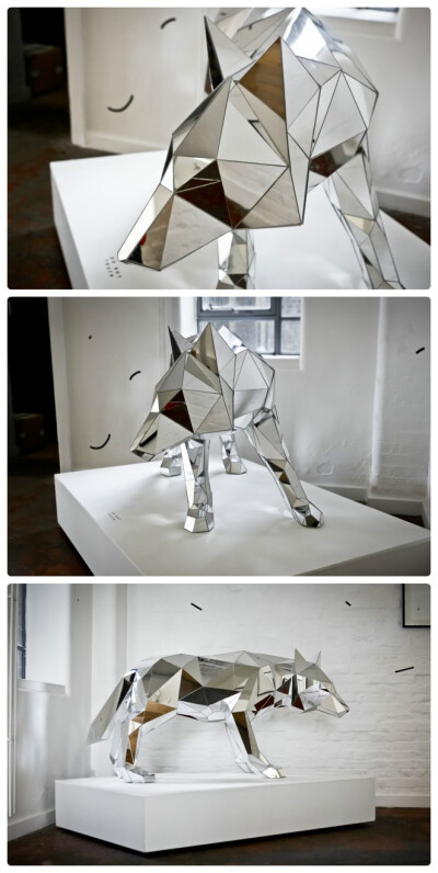 伦敦雕塑家和插画师Arran Gregory的作品中经常出现动物，最近他用反射镜面制作了一头狼。整头狼由若干块多边形镜面组成，镜面可以反射周围的环境，看上去像是一只会隐身的狼。