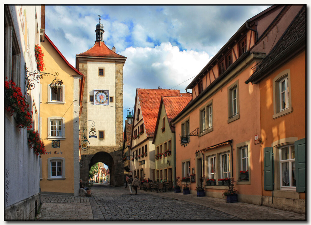 【羅騰堡Rothenburg ob der Tauber】位在德國陶伯河上的中世紀古城，歷史上幸運多次躲過戰爭得以保存完整的童話王國，市政廳為中心點道路成放射狀展開，尖尖紅瓦屋頂、德國傳統木椼建築、石磚路為主要特色，每年遊客量達150萬人次，有中世紀寶石之稱。1618年當時將軍與敵軍剎賭喝下3.25公生的葡萄酒，使此城免於戰爭，市議會宴會館(Ratstrinkstube)有人偶時鐘表演紀念那位將軍。據傳***東征後，耶穌聖血被帶到此地，存放於聖雅各教堂(St.Jakobs Kirche)內十字架的水晶球裡。其中普隆來恩廣場(Plonlein)為最具代表的拍攝景點。