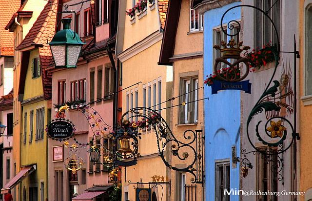 【羅騰堡Rothenburg ob der Tauber】位在德國陶伯河上的中世紀古城，歷史上幸運多次躲過戰爭得以保存完整的童話王國，市政廳為中心點道路成放射狀展開，尖尖紅瓦屋頂、德國傳統木椼建築、石磚路為主要特色，每年遊客量達150萬人次，有中世紀寶石之稱。1618年當時將軍與敵軍剎賭喝下3.25公生的葡萄酒，使此城免於戰爭，市議會宴會館(Ratstrinkstube)有人偶時鐘表演紀念那位將軍。據傳***東征後，耶穌聖血被帶到此地，存放於聖雅各教堂(St.Jakobs Kirche)內十字架的水晶球裡。其中普隆來恩廣場(Plonlein)為最具代表的拍攝景點。