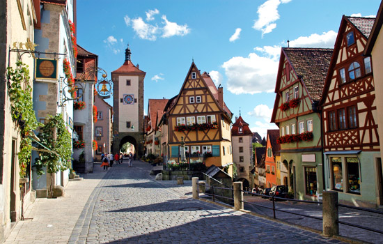 【羅騰堡Rothenburg ob der Tauber】位在德國陶伯河上的中世紀古城，歷史上幸運多次躲過戰爭得以保存完整的童話王國，市政廳為中心點道路成放射狀展開，尖尖紅瓦屋頂、德國傳統木椼建築、石磚路為主要特色，每年遊客量達150萬人次，有中世紀寶石之稱。1618年當時將軍與敵軍剎賭喝下3.25公生的葡萄酒，使此城免於戰爭，市議會宴會館(Ratstrinkstube)有人偶時鐘表演紀念那位將軍。據傳***東征後，耶穌聖血被帶到此地，存放於聖雅各教堂(St.Jakobs Kirche)內十字架的水晶球裡。此圖為普隆來恩廣場(Plonlein)最具代表的拍攝景點。