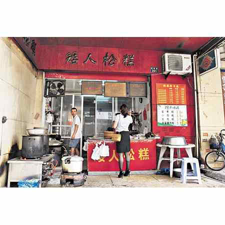 小店的名字，相信你跟我一样好奇吧，答案原来印在红胶袋子上。矮人松糕源于 20 世纪 40 年代，始创人是温州人谷进芳师傅，因人矮而糕得此名。矮人松糕曾被载入中国美食丛书、也曾获奖，后来传至第三代传人张国强，就发展出十几种松糕来。过去每户人家都自己做，后来就光顾食店。