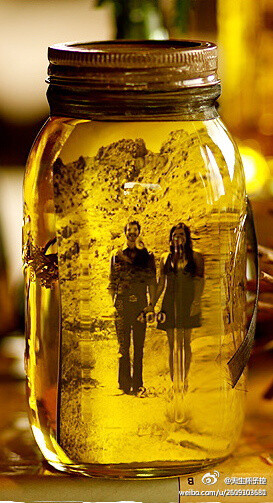 找来一个透明玻璃罐，倒入满瓶的橄榄油（色拉油），然后将喜欢的照片塞到瓶子里，盖上盖子以防油露出，这样就会出现图片中复古旧照片的感觉！手工很强大~
