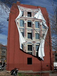 building mural. I've seen this, and it truly takes the brain some time to figure it out. It looks as if the building has been protected with some kind of cloth during restoration, and that it is being blown loose by the wind. Fantastic!