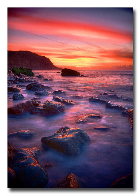 Beautifully colourful dawn sky, above the ebbing tide of Hastings beach, England