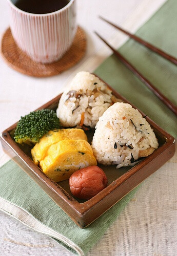 Small meal rice ball of takikomi-gohan (a rice dish seasoned with soy sauce and boiled with various ingredients), tamagoyaki (Japanese omelette), umeboshi (pickled ume), broccoli ingredients of takiko…