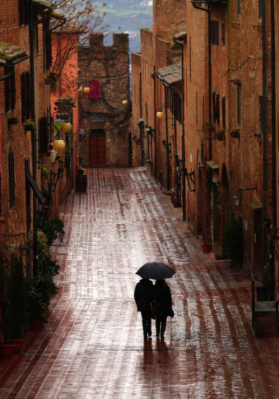 安静的街景，湿滑的路面，黑色雨伞下，两个人