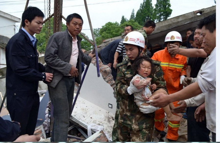 4月20日，在芦山县地震灾区，四川雅安消防救援队员从废墟里营救出一名女孩。