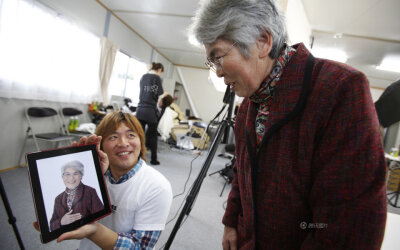 图为2011年12月，日本福岛，一个摄影师志愿者为灾民拍摄肖像。REUTERS/Yuriko Nakao