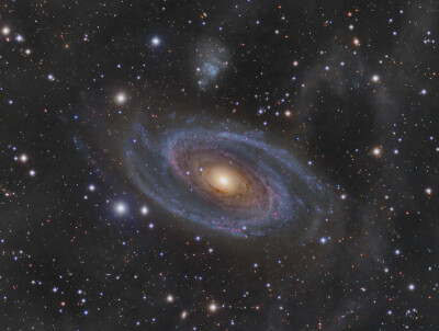 M81:和我们银河系大小相近的星系M81，位在北天的大熊座内，是个距离我们约一千一百八十万光年远的庞大美丽螺旋星系。这幅此天区的深空影像，除了亮黄色的星系核心之外，也呈现了M81壮丽蓝色螺旋臂和宽广尘埃带上的较…