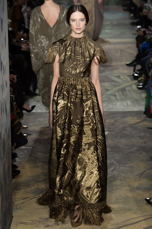 Valentino Spring2014Couture本季高级定制秀再一次选择向古典歌剧艺术致敬。开场Look就将作曲家威尔第创作的《茶花女》一曲的五线谱刺绣在半透明的绢纱长裙上；普切尼的《波西米亚人》启发了他们创作出优雅的藏蓝色开士米斗篷和真丝紧身裙；比才的《卡门》衍生出银灰色蕾丝刺绣的古铜色褶皱礼服；法国作曲家Camille Saint-Saëns创作的歌剧《动物狂欢节》更是启发设计师让天鹅、雄狮、大象、猩猩、蛇等原始丛林的物种爬上了Valentino高定的奢华礼服之上，奏出原始狂野与优雅艺术的交响曲。