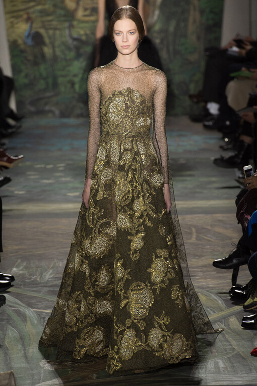 Valentino Spring2014Couture本季高级定制秀再一次选择向古典歌剧艺术致敬。开场Look就将作曲家威尔第创作的《茶花女》一曲的五线谱刺绣在半透明的绢纱长裙上；普切尼的《波西米亚人》启发了他们创作出优雅的藏蓝色开士米斗篷和真丝紧身裙；比才的《卡门》衍生出银灰色蕾丝刺绣的古铜色褶皱礼服；法国作曲家Camille Saint-Saëns创作的歌剧《动物狂欢节》更是启发设计师让天鹅、雄狮、大象、猩猩、蛇等原始丛林的物种爬上了Valentino高定的奢华礼服之上，奏出原始狂野与优雅艺术的交响曲。