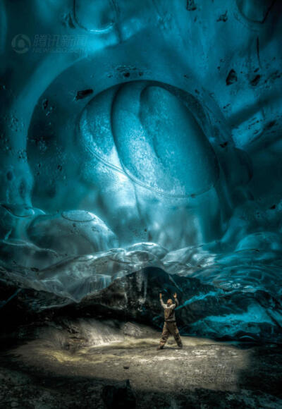 冰封奇迹 探险家拍下阿拉斯加绝美冰洞 和罗恩-吉尔同行的探险家抬头看着一处冰川锅穴。这里直通形成冰穴的冰川表面，阳光在冰川覆盖下的岩石上投下一片光斑。