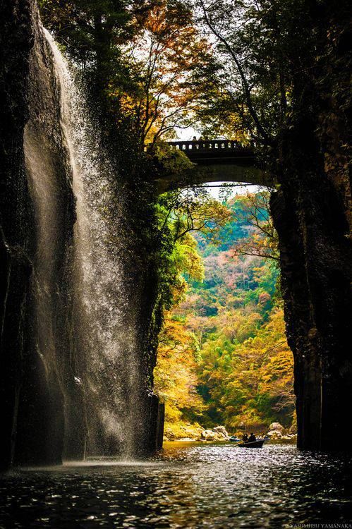 Waterfall Bridge, Takachiho Gorge, Japan。 高千穗町位于宫崎县西北部、接近九州山地的中心地带，五濑川流经村镇中心，与大分、熊本两县相邻。高千穗峡是五濑川侵蚀阿苏熔岩而形成的 V 字形峡谷，两岸沿途是略带红色的安山岩绝壁。