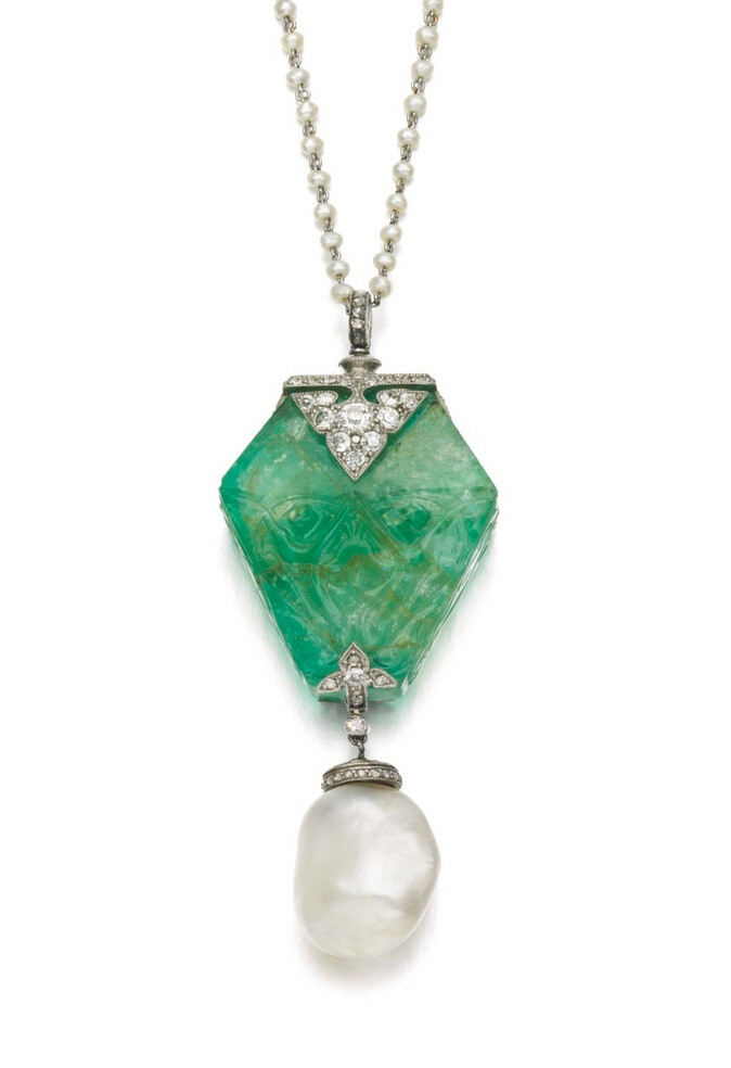 The emerald, carved in the Persian style, accented with palmette motifs and millegrain-set with circular-cut and rose diamonds, suspending a baroque natural pearl drop, later seed pearl chain, length approximately 420mm, signed Cartier, fitted case stamped Cartier.