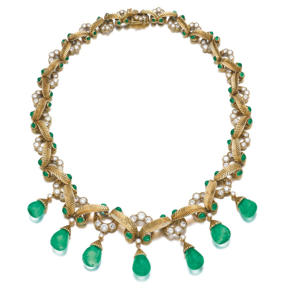 Composed of a line of stylised gold leaves, accented with cabochon emeralds and brilliant-cut diamonds, suspending a fringe of seven emerald drops, length approximately 380mm, signed Cartier Inc, numbered, French export and partial maker’s marks.