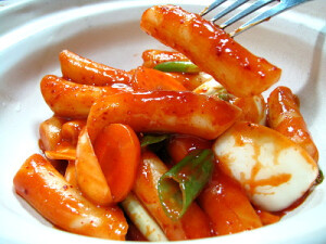 【辣炒年糕】做法：将韩式辣酱和番茄酱混合，加半碗水调匀，用大火煮开；洋葱，胡萝卜切片，鱼饼切成合适大小；辣酱汁煮开后，将年糕条下锅煮，大火煮开转为文火，依然要注意搅动；年糕4分软的时候下入洋葱，胡萝卜和鱼饼，中火熬煮，不断搅动，搅动，搅动；煮至酱汁浓稠，年糕8分软左右即可关火，出锅。