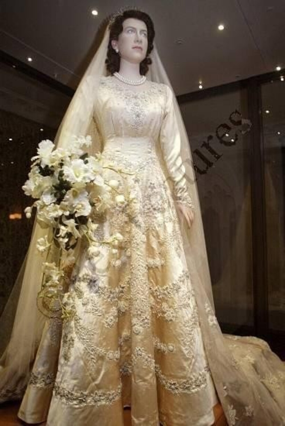 英国女王伊丽莎白二世的婚纱，出自诺曼爵士之手，婚纱上手工缝缀了一万颗珍珠。这款以文艺复兴概念设计的传统婚纱，象牙色的锦缎配上珍珠及水晶的缝纫手法以及精细繁复的手工刺绣，充分显示了“日不落帝国”的尊贵与华丽。