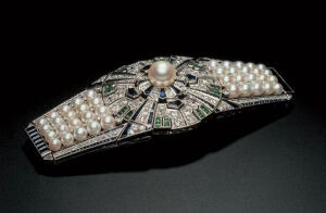 Yaguruma（矢车）于1937年在巴黎博览会上展出，这款饰扣采用多种金属及宝石制造，包括18K黄金、18K白金及铂金、共重3.48卡钻石、8.47卡蓝宝石、0.70卡绿宝石及41粒珍贵日本养珠。收藏博物馆：日本珍珠博物馆