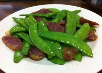 【荷兰豆炒香肠】1.荷兰豆撕去老筋洗干净。香肠放米饭里蒸好后切片。，米饭也好香啊！2.蒜头拍瘪炖碎。热锅冷油爆香蒜头，下荷兰豆大火翻炒，加少许盐调味。3.大火一定要不停快速翻炒，两分钟后加香肠片再翻下就可以…