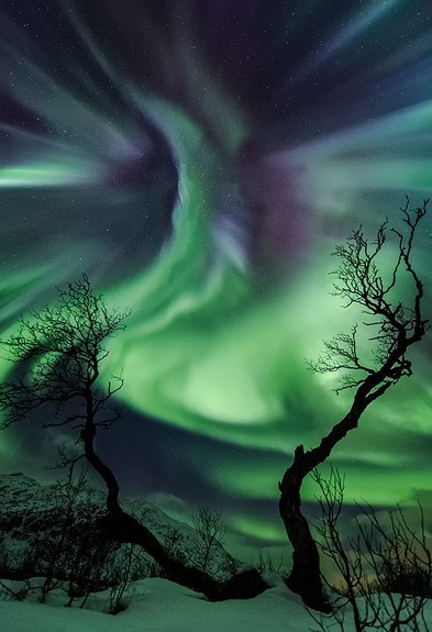 【挪威】这天是万圣节，当时天空看起来像是一种生物。－－图中生动的绿色与紫色的极光色是由高层大气中氧和氢相互作用引发的电子入射流产生的。