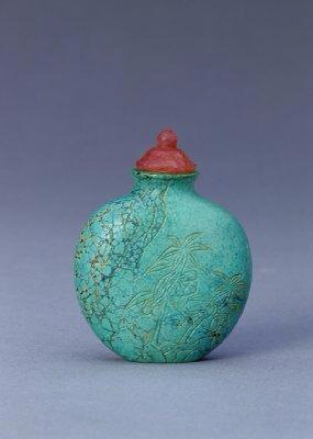  绿松石山石花卉鼻烟壶，清，通高6cm，腹宽4.8cm。 烟壶为绿松石质地，通体为蓝绿色，间有铁线斑纹。扁圆形，扁腹两面琢阴线山石花卉，并在阴线内填金。烟壶配有浅粉色芙蓉石盖，内附牙匙。 松石多块状，不透明，质地坚硬且脆，颜色多为鲜艳的天蓝色或蓝绿色，此作品为蓝绿色。