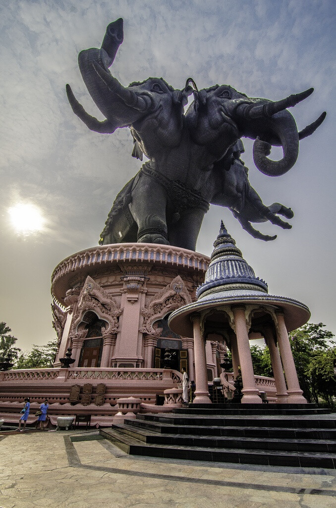 Giant elephants at the entrance to Erawan Museum in Bangkok, Thailand。在位于泰国的北榄府，距离曼谷新国际机场不远，从路边远远就可以看见重达250吨、高16层楼的三头庞然巨物，它是纯铜精雕而成的神象，那就是爱侣湾三象神博物馆所在，是目前泰国境内唯一一座三象神博物馆。