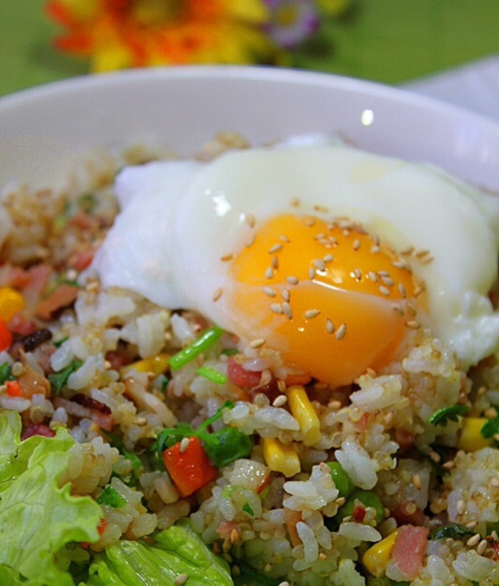 （溏心蛋藜麦炒饭）食材：煮熟的藜麦米饭、鸡蛋、培根、香菇、杂菜、香菜、芝麻、橄榄油、做法：香菇泡发清洗干净后切碎.培根也切碎备用.香菇和培根先倒入平底锅.加少量橄榄油煸炒.使培根的油脂充分析出.撒少许胡椒粉.倒入杂菜.翻炒.倒入藜麦饭.继续翻炒.加盐调味.撒香菜叶.盘底垫生菜.或不垫.将炒饭盛盘.新鲜鸡蛋先在水中煮到溏心捞出.放在米饭上.撒芝麻.即可食用了。