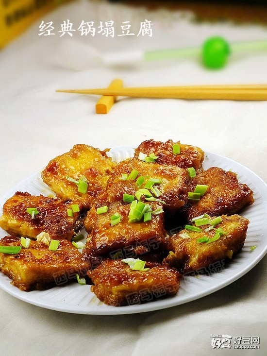 食材：北豆腐200g鸡蛋2个 盐2g白胡椒2g酱油1勺糖3g鸡汤1碗淀粉适量食用油适量葱末适量 步骤1、将豆腐洗净沥干，切成0.6厘米厚、3.3厘米见方的块。 2、放入盘内，加盐 白胡椒拌匀。 3、煎锅放油烧至七成热。 4、豆腐片入淀粉粘匀。 5、再将每片豆腐均粘匀鸡蛋液。 6、逐片下入七成热的油内。 7、剩下的蛋液均匀的倒在豆腐上。 8、煎至一面金黄翻面再煎另一面。 9、煎至两面金黄，倒入鸡汤。 10、烧开加入酱油 糖小火焖至。 11、汤汁收干勾入薄芡， 12、表面撒上葱碎即可。 小贴士：豆腐片要切大小薄厚一致，锅煽豆腐要用微火慢煽。