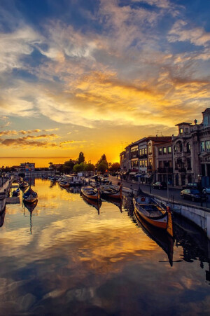 Sunset in Aveiro, Portugal (by Jorge Orfão)。阿威罗，是葡萄牙中北部新兴城市，位于葡萄牙中部大西洋沿岸，是沟通葡萄牙中部与北部的交通枢纽。阿威罗也是一座著名的水城，有“葡萄牙的威尼斯”之称：美丽的小桥连接着水道运河，河中五彩缤纷的贡多拉和快艇在水上来回穿梭，水道两边很多18世纪遗留下来的商铺，在那里，你可以听到各种各样的音乐。而最惬意的则在夏夜安坐于贡多拉上，倾听着两岸传来的夜曲。除了这些，阿威罗丰富的历史古迹，华丽的海滩和美味的菜肴也是吸引众多游客到此一游的原因。