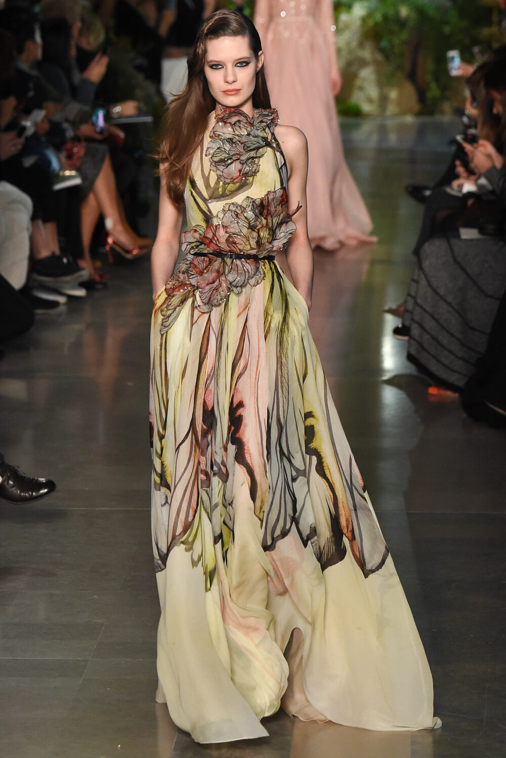 Elie Saab Spring 2015 Couture。艾莉·萨博2015春夏巴黎高级定制时装周在一片片绿色植被花丛中拉开帷幕。本季，以“忧伤的挽歌”向家乡贝鲁特致敬，Elie Saab以“花”为主题，重笔墨于轻盈的流苏与立体花朵装饰之上，结合他对美的深刻理解，用亮片刺绣点缀于薄纱中，轻绢曼纱、珠罗蕾丝，宛若花仙精灵，美得令人窒息。
