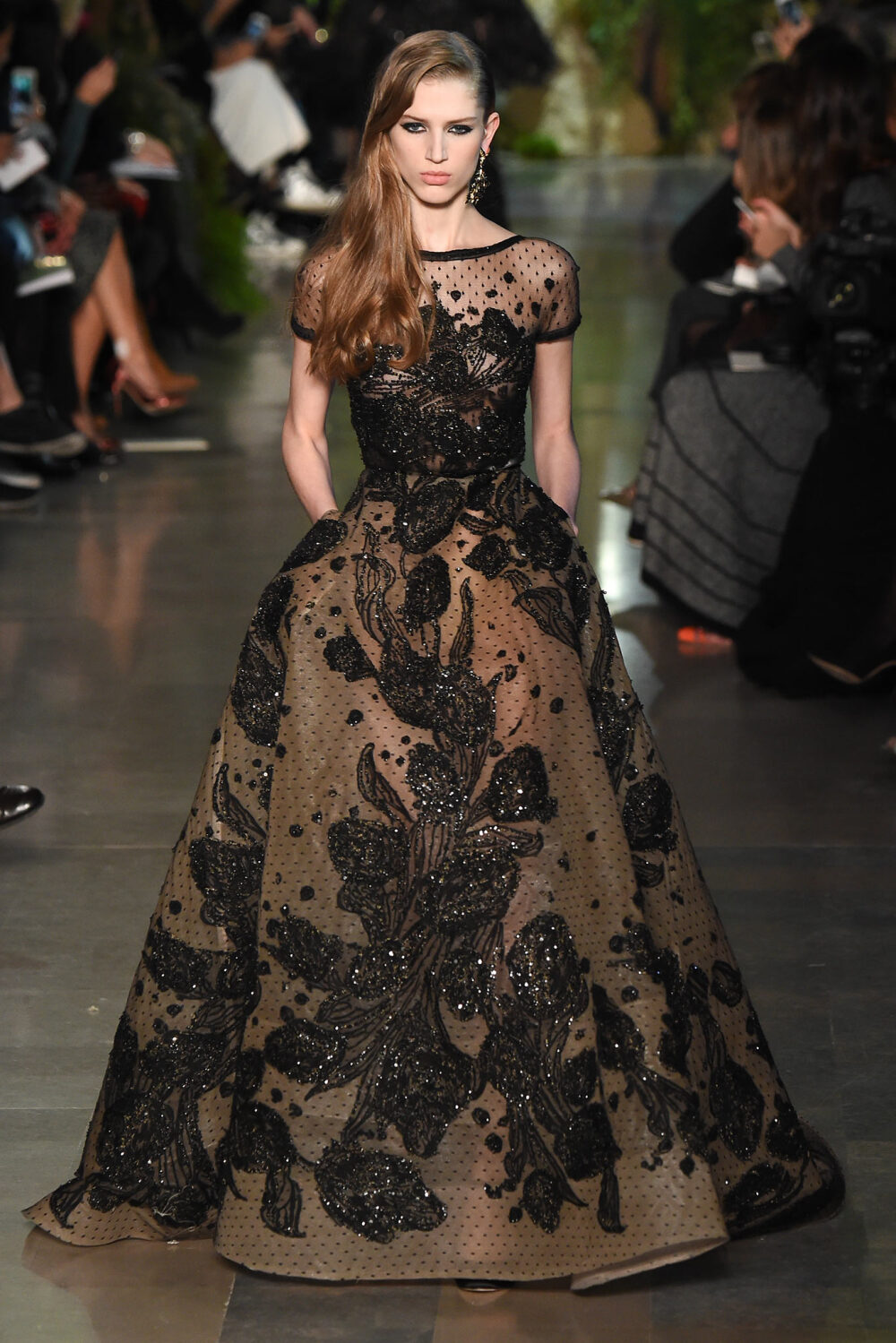 Elie Saab Spring 2015 Couture。艾莉·萨博2015春夏巴黎高级定制时装周在一片片绿色植被花丛中拉开帷幕。本季，以“忧伤的挽歌”向家乡贝鲁特致敬，Elie Saab以“花”为主题，重笔墨于轻盈的流苏与立体花朵装饰之上，结合他对美的深刻理解，用亮片刺绣点缀于薄纱中，轻绢曼纱、珠罗蕾丝，宛若花仙精灵，美得令人窒息。