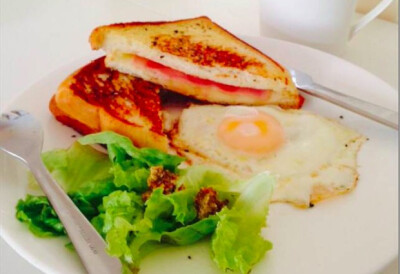 【简易版Croque Monsieur 法式三明治】 面包片 2片 芝士片 1片（可适当加多） 火腿 1~2片（个人喜好） 黄油 适量 千层塔 适量 简易版Croque Monsieur 法式三明治的做法 首先把面包片在不粘锅上面烤脆些，注意…