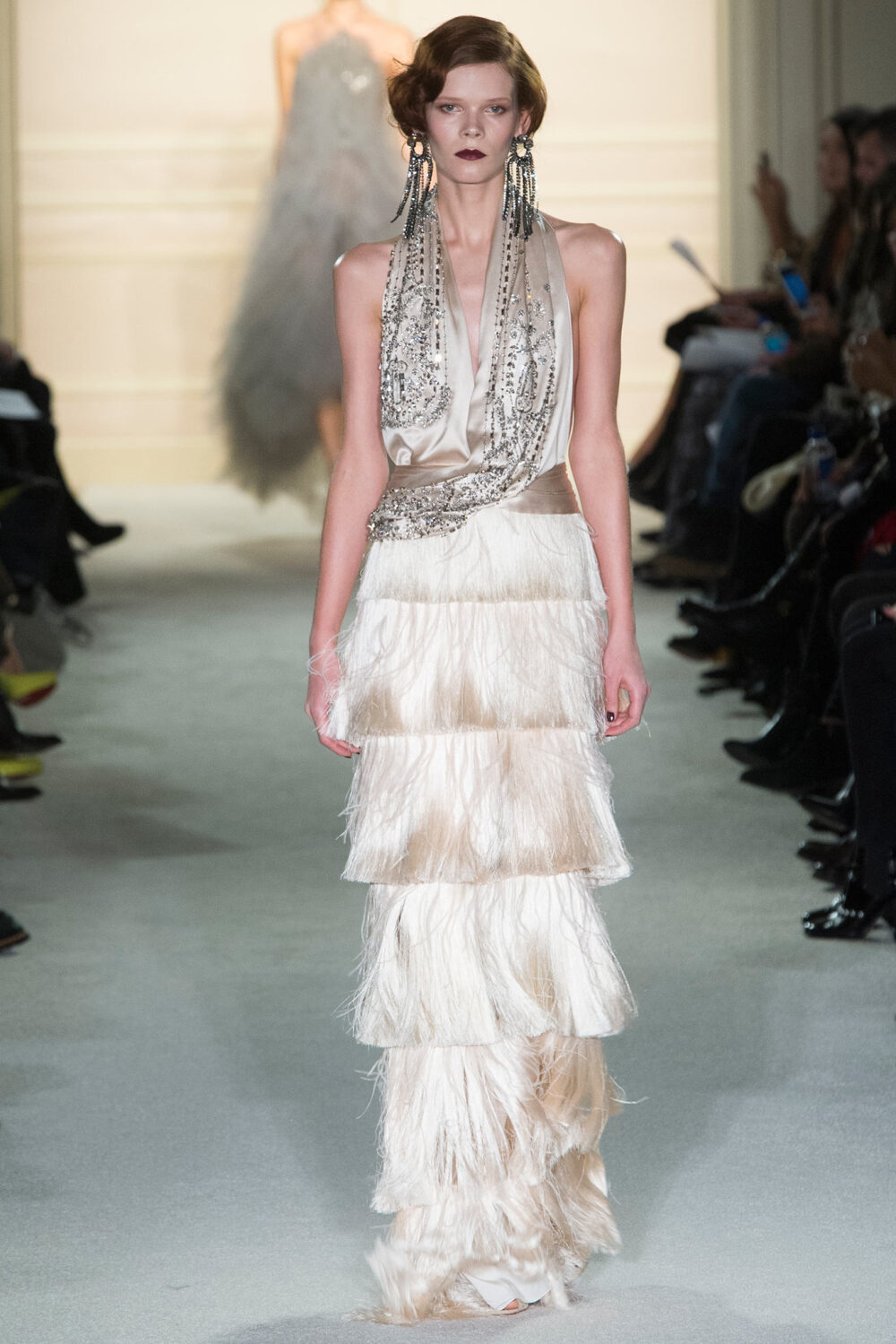 Marchesa Fall 2015 Ready-to-Wear。玛切萨2015纽约时装周秋冬女装秀华丽大胆、恣意风情，像20年代巴黎的名贵水粉，也像美国“爵士时代”漫天的纸醉金迷；像戏梦人生的巴黎交际花，也像菲茨杰拉德笔下的“盖茨比”女郎——如真也似幻。流苏的裙摆窸窣摆动起来，裸露的肌肤闪亮起来，周身的羽毛飞舞起来，媚态饱满的眉眼斜乜起来。Flapper女郎们又仙又接地气儿，明天再说明天的！狐步舞立刻跳将起来——欲望，你好；沉闷，再见！