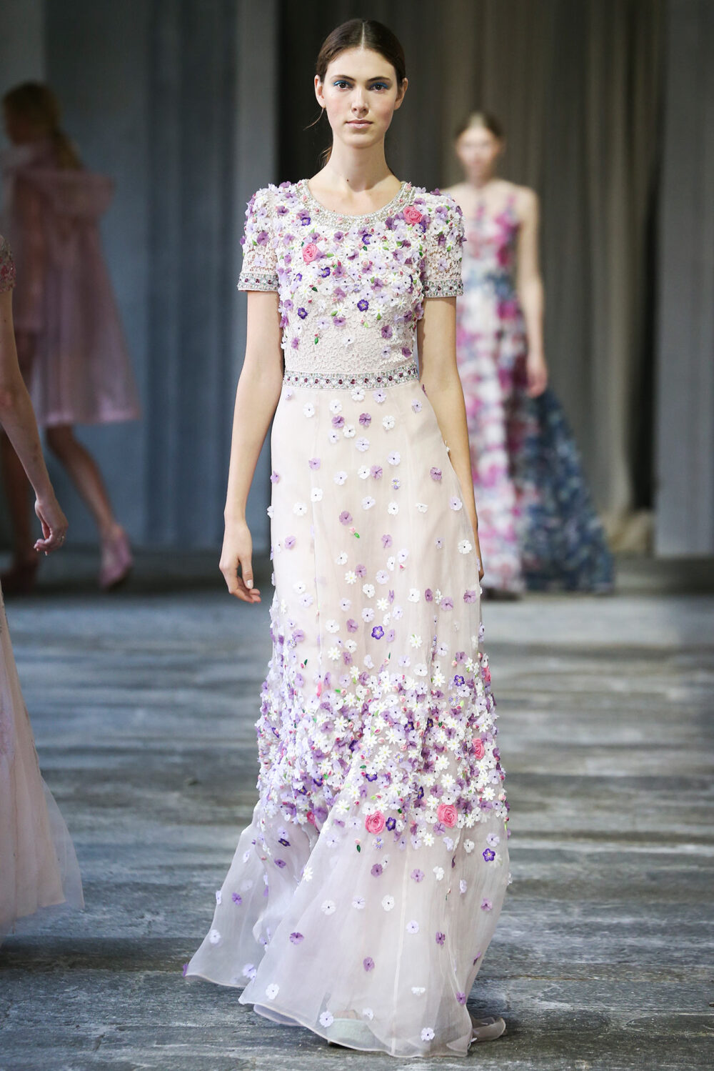 Luisa Beccaria Spring 2015 Ready-to-Wear。路易莎·贝卡里亚2015米兰时装周春夏高级成衣发布。在鲜向公众开放的圣辛普立西阿诺修道院，其漂亮的院子中举办的一场展示兼时装秀，向其出身名门的米兰朋友打招呼。身穿如舒芙蕾一样精致的连衣裙的模特们分散在静谧的花园中一道修道院的拱廊下，周围是喷泉的滴滴答答以及唱片上直抵灵魂的音乐在流淌。这营造了一种唤起前尘往事的背景气氛，非常适合展示这种已经得到认可的属于豪华婚礼和高门槛的元媛舞会中的完美风格。