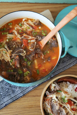 【酸汤肥牛】 做法 肥牛提前解冻，蒜拍破后切碎，青红尖椒切圈，金针菇剪去根部洗净 2 将金针菇放入加了几滴油的开水锅中烫熟，滤干水份放入碗中铺好 3 炒锅内倒入少量油，烧至六成热后，放入姜片、蒜碎爆香 4 放入黄灯笼辣椒酱翻炒一分钟，加入高汤，料酒大火煮开 5 用网筛滤掉锅内的料渣丢掉，放入肥牛片，加入盐，糖煮开，将煮出的浮沫也用网筛滤掉 6 待肥牛煮熟后，淋上白醋，关火，将其倒入铺了金针菇的盘中 7 表面撒上青红椒圈点缀，最后烧少量热油淋在青红椒圈上即可